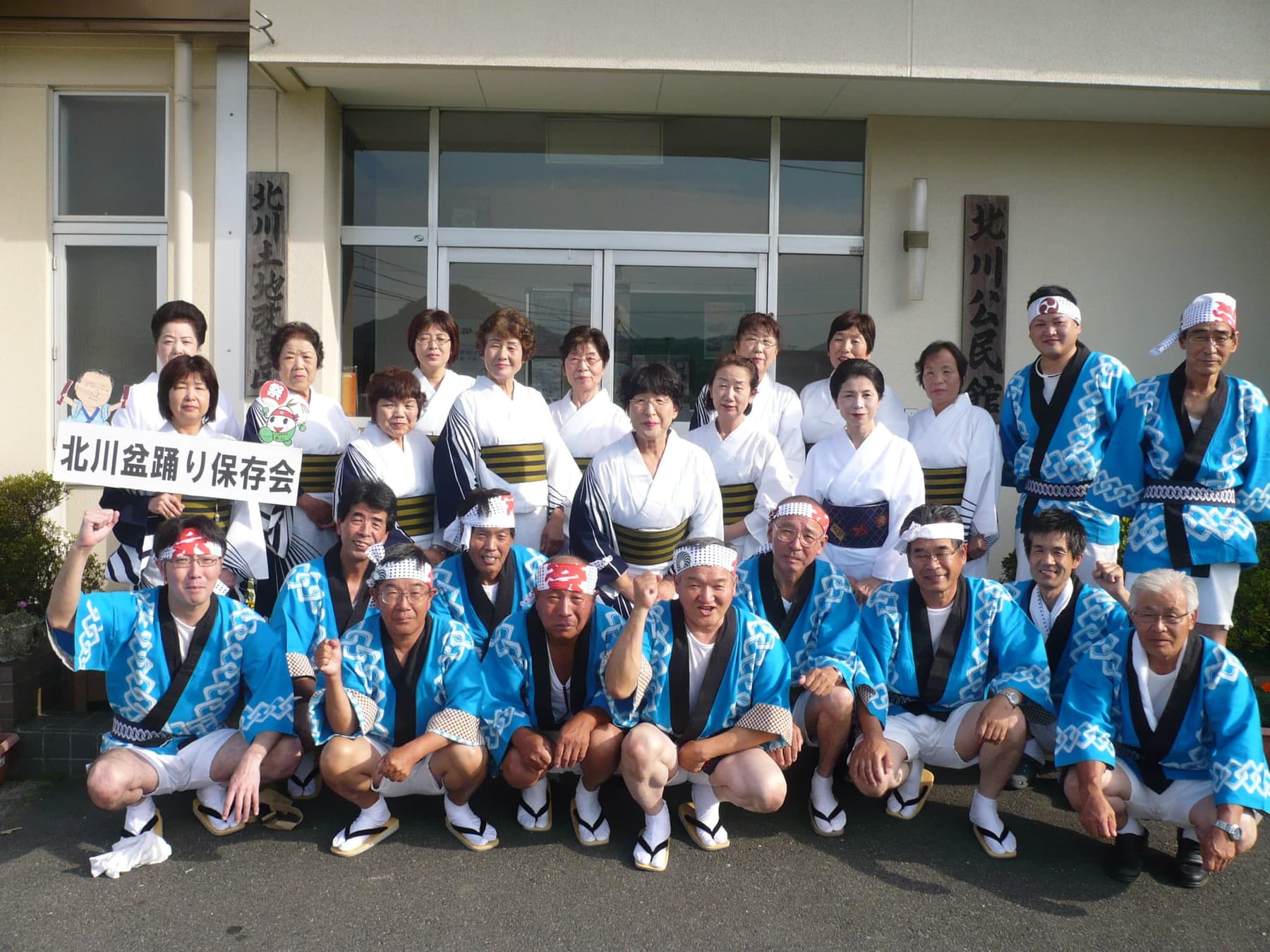 法被と浴衣姿の保存会のみなさんが、北川公民館の前に並んでいる